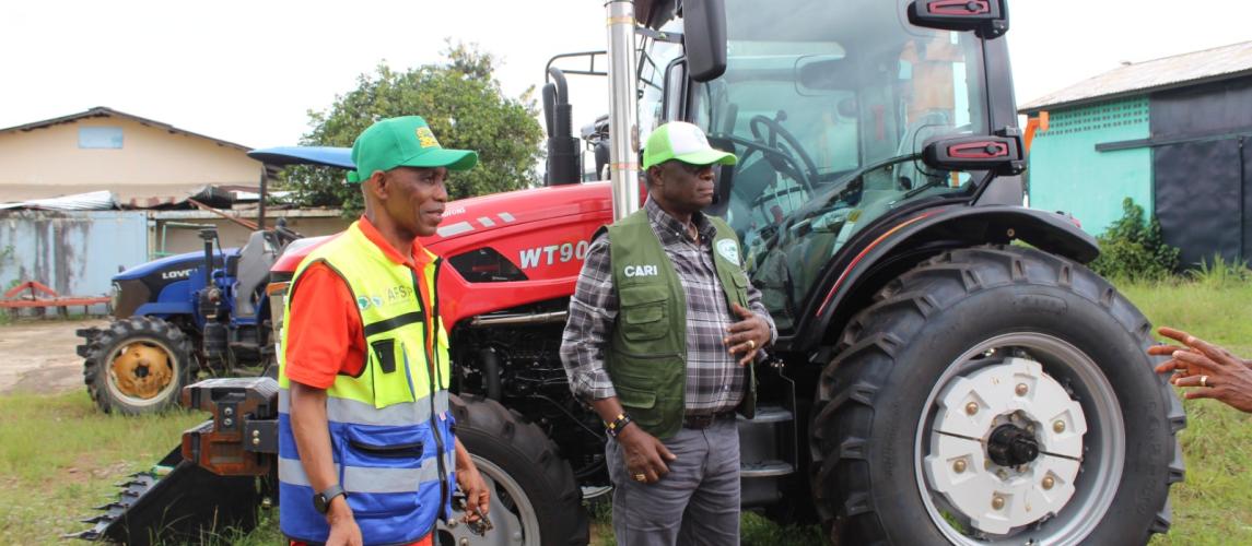 Dr. Arthur Bob Karnuah, Director General of CARI, and Daniel Wiagbe, National Coordination Officer of the SADFONS Project, pose together during the official handover of advanced 90‑horsepower tractor accompanied by multiple implements, power tillers, and motorized sprayers.